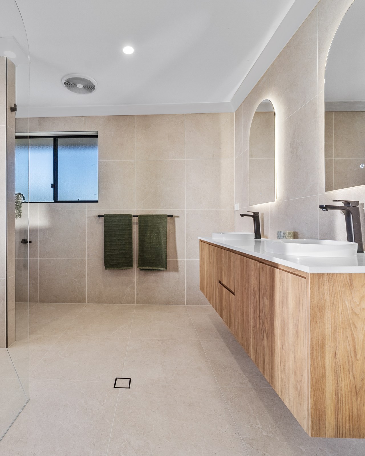 Completed Munreno bathroom — floating timber vanity, arch mirrors and walk-in shower
