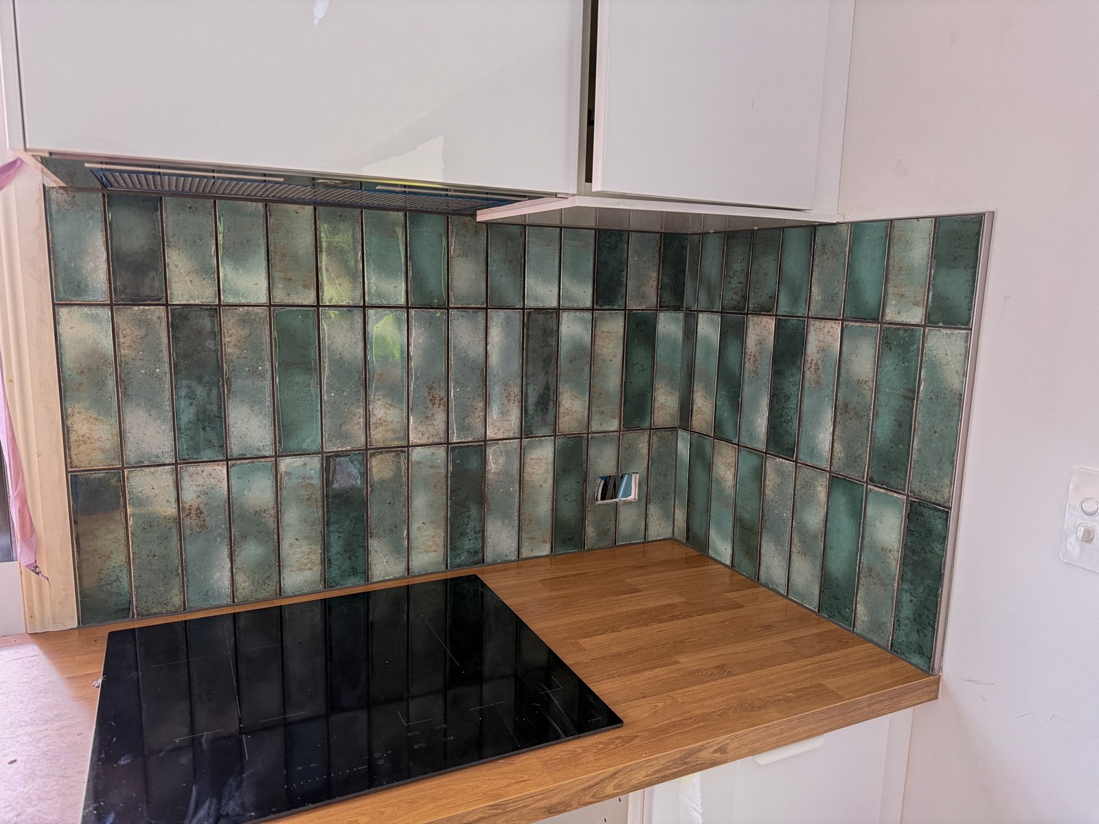 Kitchen splashback in handmade-look green tile above a timber benchtop
