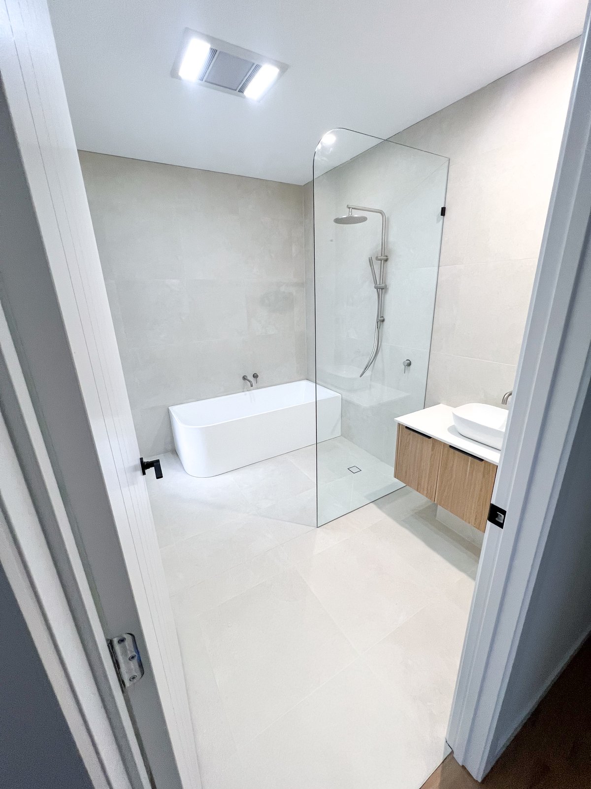 New-build bathroom with stone-look walls, freestanding bath and seafoam feature tile