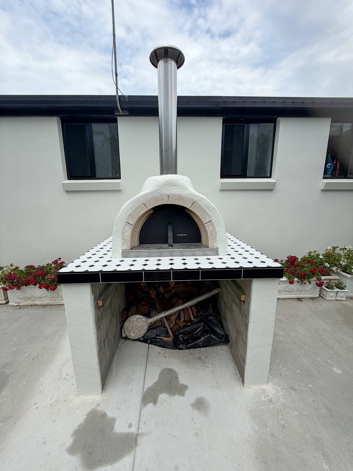 Rendered outdoor pizza oven with a black-and-white tiled bench