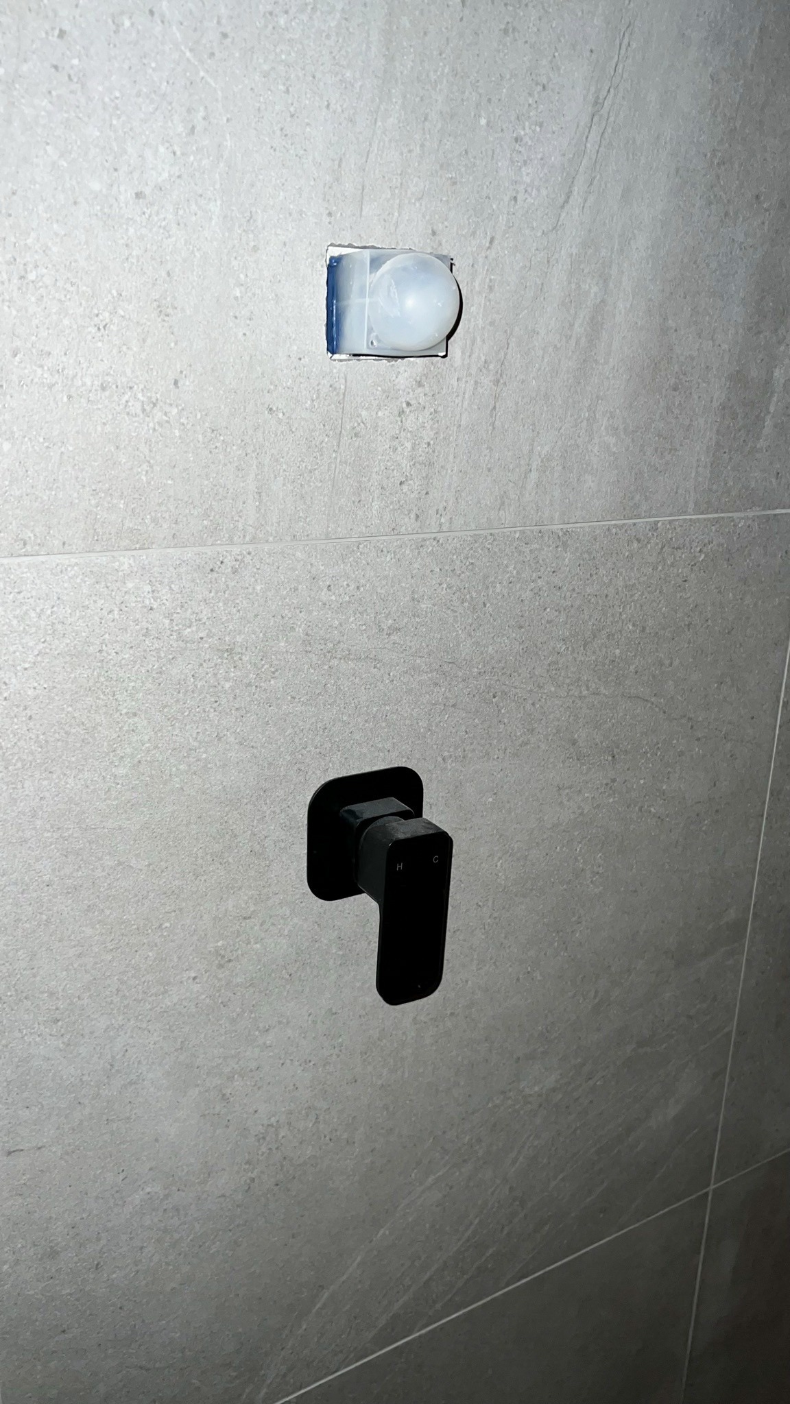 Matte black mixer set against grey stone-look tile