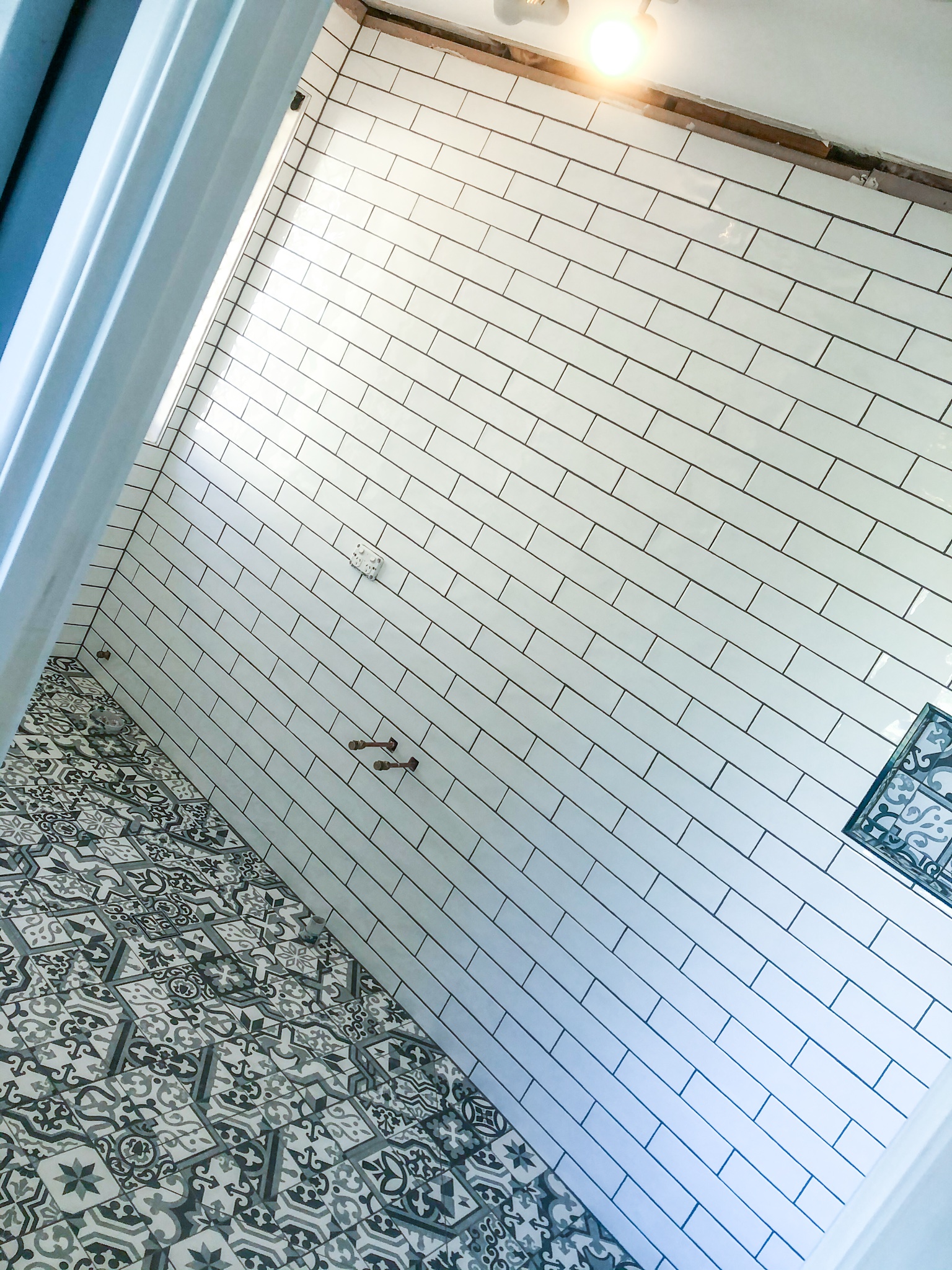Subway wall tiling in progress, feature-tile niche framed and lined