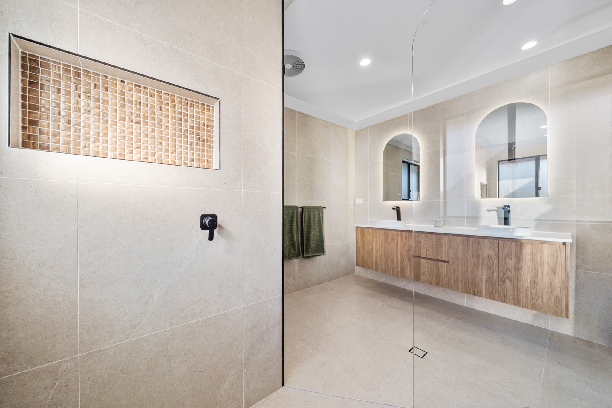 Floating timber vanity with vessel basins under backlit arch mirrors